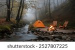 Cozy campsite by a stream with a tent and campfire in foggy woods.