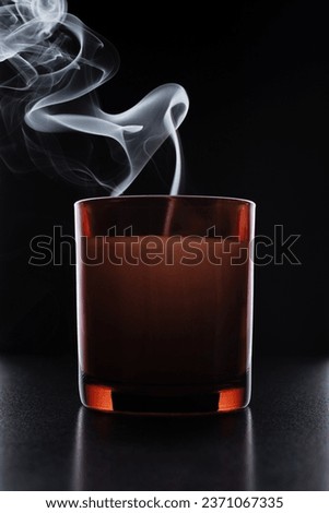 Cozy candle in brown glass jar with smoke on dark background