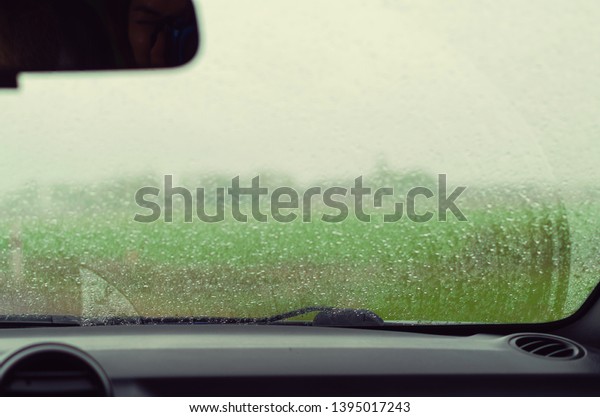 A cozy car inside. Blurred rain drops\
on a car wind screen. Traveling by car in summer.\
