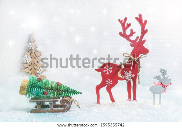 Cozy chrismtas and new year composition. Red deer\
carring the sled with christmas tree. Fresh snow, white background\
with flare
