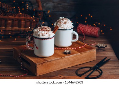 Cozy Christmas composition.Two mug with hot drinks, chocolate with whipped cream and cinnamon stick on a dark wooden background. Sweet treats for cold winter days. - Powered by Shutterstock