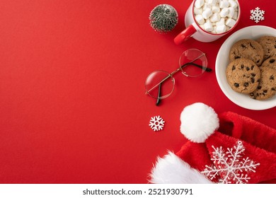 A cozy Christmas scene featuring a Santa hat, glasses, cookies, and a mug of hot cocoa with marshmallows on a red background - Powered by Shutterstock