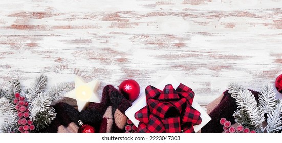 Cozy Christmas Or Winter Bottom Border With Red, Black And Beige Sweater, Gift Box, Candle, Frosty Tree Branches And Decor. Top Down View Over A Rustic White Wood Banner Background. Copy Space.