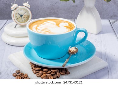 A cozy coffee scene featuring a latte art swan in a blue cup and saucer. Includes coffee beans, a spoon, an alarm clock, and a vase on a wooden table. Inviting and serene atmosphere. - Powered by Shutterstock