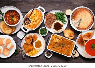 Cozy comfort food table scene. Overhead view over a dark wood background. Meatloaf, stew, pot pie, mac and cheese, grilled cheese, soup, fried chicken, shepherds pie and warm sides. - Powered by Shutterstock