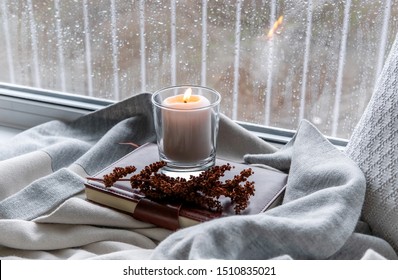 A Cozy Corner In The House. Candle And Rain Drops On The Window.