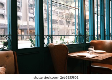 Cozy corner table by the window in a European-style brunch restaurant in Hong Kong, set with plates and glasses, overlooking the city street.