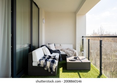 Cozy Decorated Balcony With Big Window Doors To Apartment, Synthetic Grass And Stylish Rattan Corner Sofa With Decorative Pillows And Rattan Coffee Table