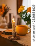 Cozy dining table with a warm autumnal atmosphere featuring a yellow cup, an open book, a muffin, and decorative vases with yellow flowers. The scene evokes a sense of relaxation and comfort.