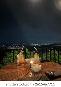 Cozy dinner setup with a stunning backdrop of city lights at night, creating a peaceful and intimate atmosphere. Perfect for themes of romantic dining, urban lifestyle, and special moments