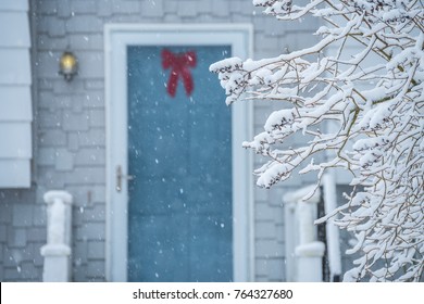 A Cozy Door And Porch Of A Small House During A Snowfall. Branches Of Plants Covered With Fluffy Snow. USA. Maine. The Atmosphere Of A Beautiful White Winter And Home Comfort
