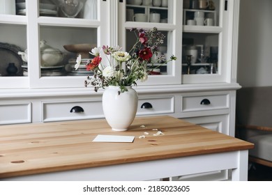 Cozy elegant Swedish Scandinavian style living room, home office. Vintage white cupboard with crockery. Wooden table. Vase of zinnia, cosmos and dahlia flowers and blank greeting card. Linen sofa. - Powered by Shutterstock