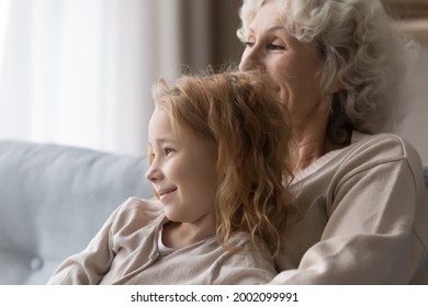 In Cozy Embraces Of Grandma. Adorable Girl Grandchild Relax On Couch In Loving Granny Arms Listen To Stories Wise Advices. Smiling Preteen Girl Feel Emotional Bonding With Caring Aged Female Custodian