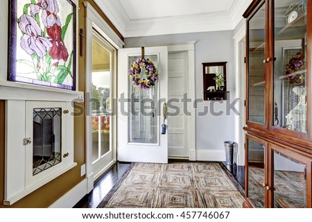 Cozy entry room in small craftsman house with decorative window and vintage cabinet with glass doors.