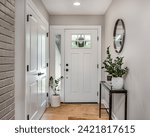 A cozy entryway with brown and brick walls, hardwood flooring, decorations, and a white front door with windows.