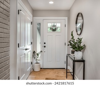 A cozy entryway with brown and brick walls, hardwood flooring, decorations, and a white front door with windows. - Powered by Shutterstock