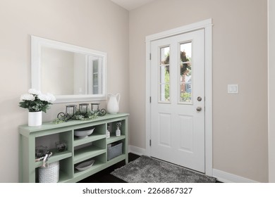 A cozy entryway with brown walls, a green console table with decorations, and a white front door. - Shutterstock ID 2266867327