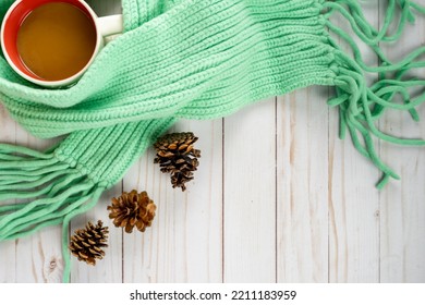 Cozy Fall Arrangement With A Coffee Cup, Teal Cable Knit Scarf, And Pine Cones On A Wood Background