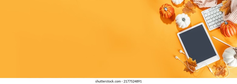 Cozy fall background with tablet, ear-pods, white, orange pumpkins, autumn leaves decor on high-colored orange background. Autumn still life composition.  - Powered by Shutterstock