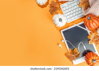 Cozy Fall Background With Tablet, Ear-pods, White, Orange Pumpkins, Autumn Leaves Decor On High-colored Orange Background. Autumn Still Life Composition. 