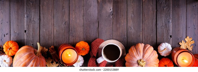 Cozy fall bottom border with pumpkins, sweaters, candles and coffee. Top view over a dark wood banner background. - Powered by Shutterstock