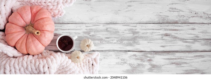 Cozy Fall Corner Border On A Rustic White Wood Banner Background. Top View. White Blanket, Spiced Tea, Pink And White Pumpkins.