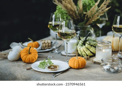 Cozy fall table decoration for Thanksgiving family dinner or romantic autumn wedding outdoors with small pumpkins, candles. White wine. Countryside style, cottage core, beautiful elegant setting - Powered by Shutterstock
