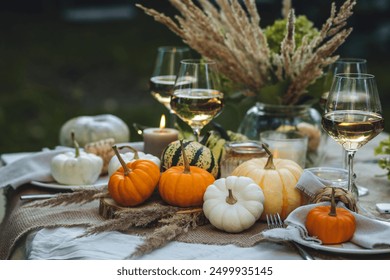 Cozy fall table decoration for Thanksgiving family dinner, romantic autumn wedding outdoors with small pumpkins, candles. White wine. Countryside style, cottage core, beautiful elegant setting - Powered by Shutterstock