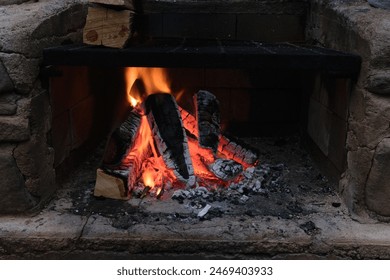 A cozy fireplace with burning logs and glowing embers, surrounded by a stone hearth. - Powered by Shutterstock