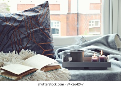 Cozy Home With Cup Of Tea With Steam, Blanket, Book And Candles. Hygge Home Interior