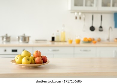 Cozy home kitchen design and comfortable style, ad for rent. Plate with apples on table, bottles of sauces and utensils, orange juice in glasses and fruits, light walls and white furniture, copy space - Powered by Shutterstock
