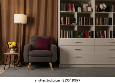 Cozy Home Library Interior With Comfortable Armchair, Floor Lamp And Collection Of Books On Shelves