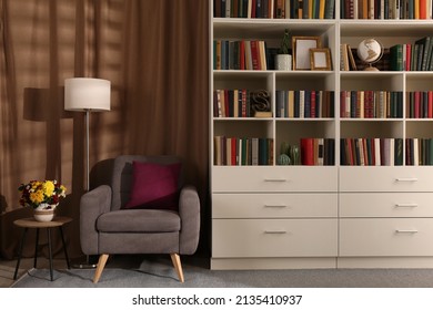 Cozy Home Library Interior With Comfortable Armchair, Floor Lamp And Collection Of Books On Shelves