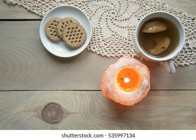 Cozy Home Still Life. Candle Of Pink Salt With Fire, A Cup Of Apple Compote And Plate With Cookies On Knitted Napkin On A Light Wooden Background. Top View.