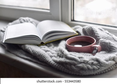 Cozy Home Still Life: Cup Of Hot Coffee And Opened Book With Warm Plaid On Windowsill Against Snow Landscape Outside. Winter Holidays, Christmas Time Concept, Free Copy Space