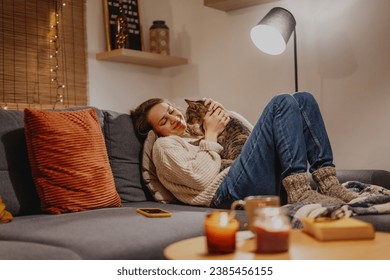 Cozy at home with tabby cat, woman with her pet on sofa ay home in evening, Winter holidays  concept - Powered by Shutterstock