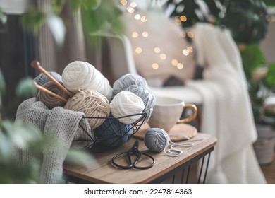 Cozy homely atmosphere. Female hobby knitting. Yarn in neutral colors in a white iron wire basket. The beginning of the process of knitting a women's sweater. Blurred bokeh