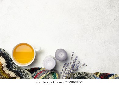 Cozy Hygge style composition with handmade woolen plaid, herbal tea, candles and dry lavender bouquet on white marble background, copy space for your design.