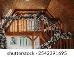 The cozy interior of a wooden cabin showcases festive decorations, including garland and Christmas trees, creating a warm atmosphere perfect for the holiday season.