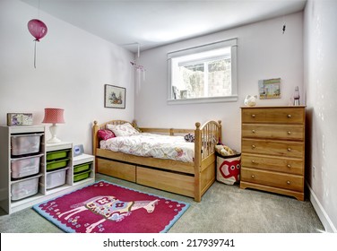 Cozy Kids Room With Rustic Bed And Dresser. Cheerful Red Rug On Carpet Floor