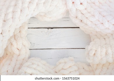 Cozy Knitted Thick Wool Blanket. Top View Frame On A White Wood Background With Copy Space. Cream Color.