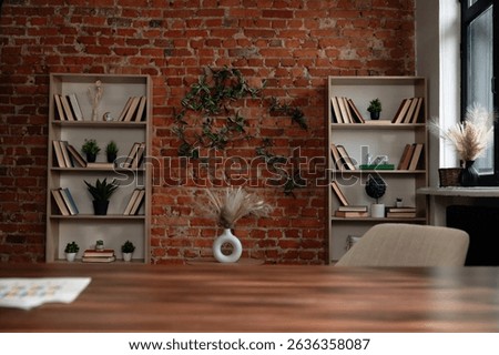 A cozy library setting featuring two bookshelves against a rustic brick wall, adorned with plants and books.