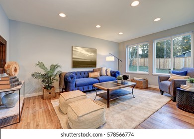 Cozy Light Filled Living Space Accented With Blue Tufted Sofa Facing Reclaimed Wood Cocktail Table Atop Soft Beige Rug And Finished With Green Plant In A Wicker Box. Northwest, USA