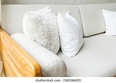 Cozy light gray sofa with white pillows and wooden armrest. Horizontal photo - Shutterstock ID 2185586035