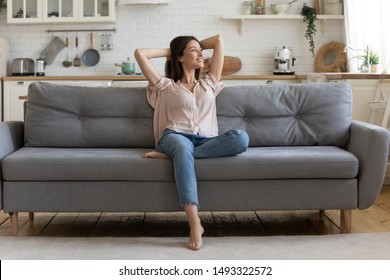 In cozy living room happy woman put hands behind head sitting leaned on couch 30s european female enjoy lazy weekend or vacation, housewife relaxing feels satisfied accomplish chores housework concept - Shutterstock ID 1493322572