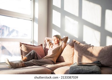 In cozy living room happy woman put hands behind head sitting leaned on couch 40s european female enjoy lazy weekend or vacation, housewife relaxing feels satisfied accomplish chores housework concept - Shutterstock ID 2133387039