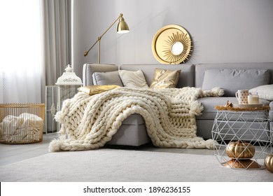 Cozy living room interior with knitted blanket on comfortable sofa