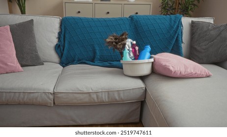 A cozy living room with a light-gray sofa adorned with pink and gray pillows, a teal throw, and a cleaning supplies basket, creating a tidy and welcoming home environment. - Powered by Shutterstock