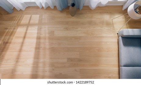 Cozy Living Room With Modern Interior, Grey Sofa And Wooden Flooring Lit By Warm Light Out Of The Window. Top View Camera Shot.