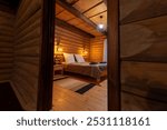 Cozy log cabin bedroom with wooden walls, a double bed, and warm lighting.